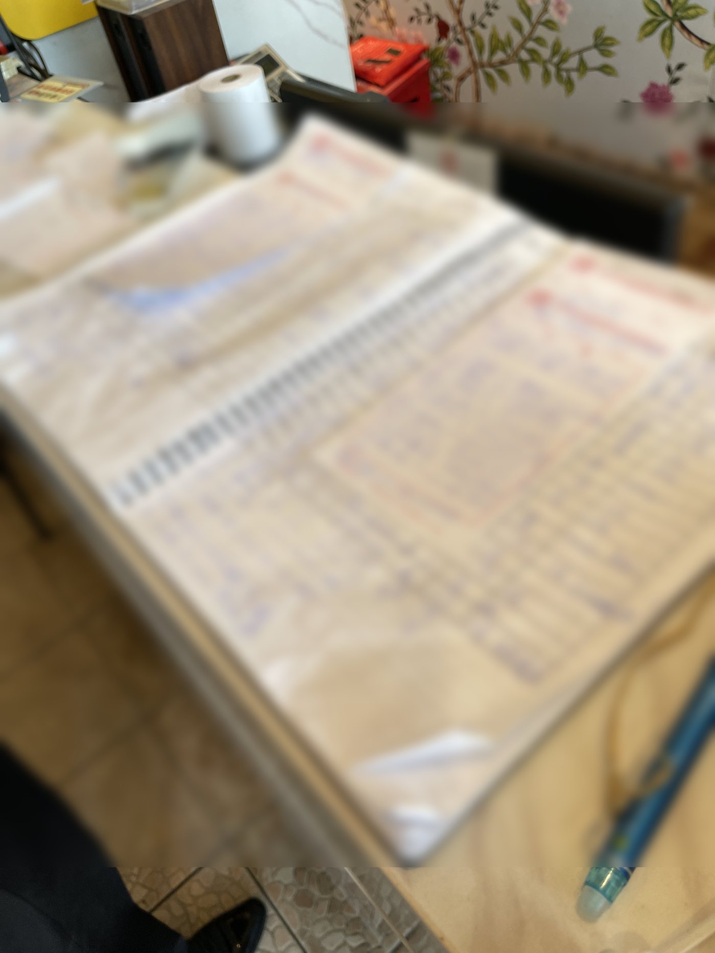 A spiral ledger of handwritten bookings and order slips at a restaurant front desk, blurred