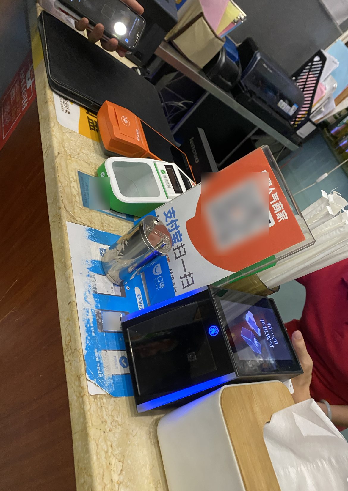 A checkout counter with several payment devices and QR code stands from different platforms